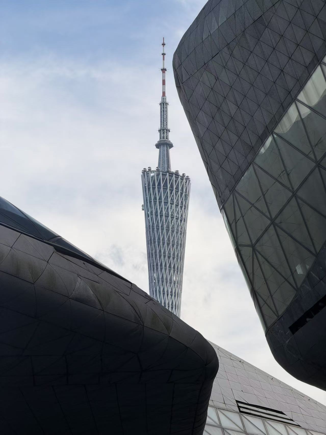 从深灰色建筑之间仰望广州塔