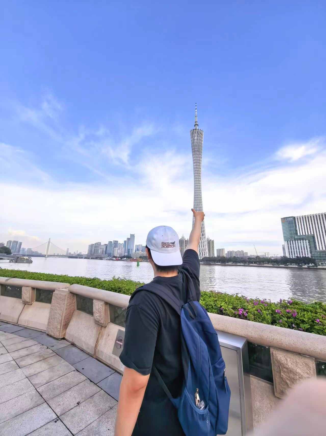 江边的人举手与远处广州塔错位合影